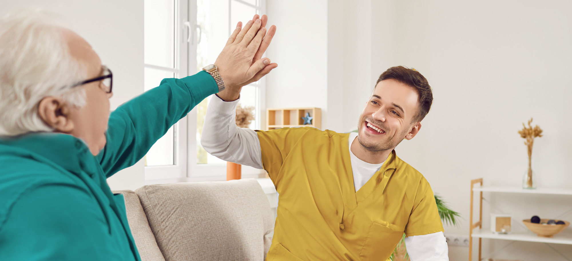 Pflegekraft und Senior geben sich ein High Five – Symbol für Vertrauen und Lebensfreude im Alltag
